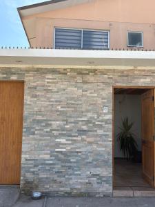 a house with a brick wall and an open door at Casa de Melinka in Mejillones