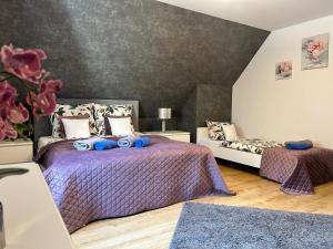 a bedroom with two beds with purple comforters at Emilia domki U Przyjaciół in Żarnowska