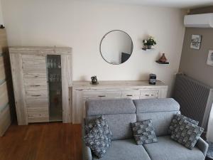 a living room with a gray couch and a mirror at BERGERAC Chez Béa in Bergerac
