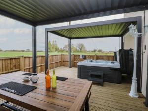 a patio with a table and a tub on a deck at Aloe Lodge in Diss