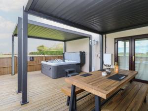 a patio with a table and a grill on a deck at Aloe Lodge in Diss +16 photos