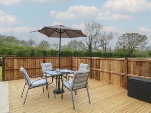 a patio with a table and chairs and an umbrella at Aloe Lodge in Diss