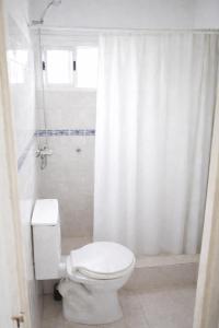 a white bathroom with a toilet and a shower at Hospedaje Don Felix in General Acha