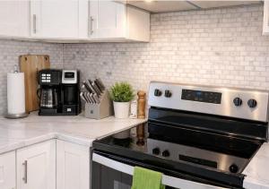 a kitchen with white cabinets and a stove top oven at Spacious Home with Fire Pit & Game Room Near Yale in Hamden