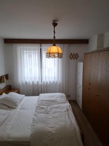 a bedroom with a white bed and a chandelier at Campiglio Trilocale Monte Spinale in Madonna di Campiglio