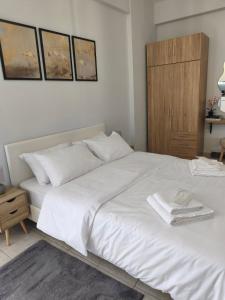 a bedroom with a white bed with a wooden cabinet at Lounetta Apartments 2 in Missolonghi