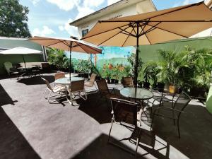 a patio with tables and chairs and umbrellas at Woodbrook on the Avenue in Port-of-Spain