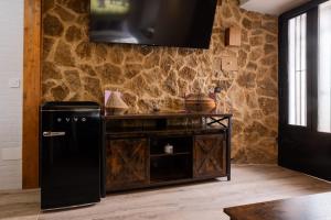 a kitchen with a black refrigerator and a stone wall at REFUGIO De PERNACIO in Ávila