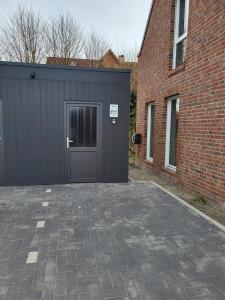 a garage with a door next to a brick building at Ferienwohnung Schöne Aussicht in Hinte