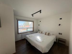 a bedroom with a large white bed with a window at Apartamentos Entre Fronteras in Punta Arenas