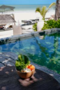 a bowl of vegetables sitting on a table next to a pool at Nômade Temple Holbox in Holbox Island