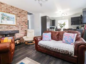 a living room with a leather couch and a brick wall at Southview Bungalow in Barmston