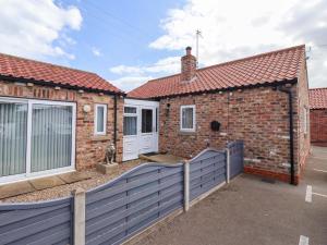 a brick house with a blue fence in front of it at Southview Bungalow in Barmston