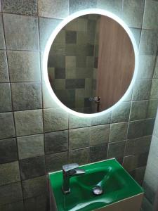 a bathroom with a green sink and a round mirror at Aianteio Square Resort -SPA in Aiándion +14 photos
