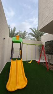 a playground with a slide and a swing at فلل وشاليهات لفونيا in Buraydah
