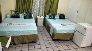 two beds in a room with green curtains at Woodbrook on the Avenue in Port-of-Spain