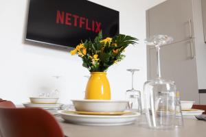 a table with a yellow vase with yellow flowers on it at Moderno Bilocale Con Parcheggio Privato in Piacenza +16 photos