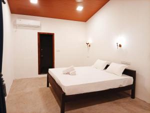 a bedroom with a bed with white sheets and a wooden ceiling at Cozy Vibe Villa in Arugam Bay