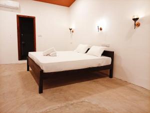 a bed with white sheets and pillows in a room at Cozy Vibe Villa in Arugam Bay +7 photos