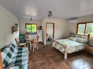 a bedroom with a bed and a kitchen with a table at Chalés Jatobá in Areias