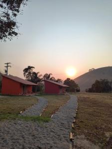 a road leading to a house with the sunset in the background at Chalés Jatobá in Areias