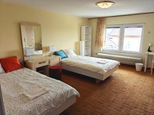 a bedroom with two beds and a desk and a window at Angela Hostel in Fram