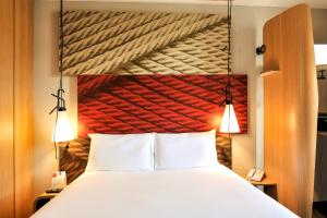 a bed with a white bedspread and pillows at Ibis Schiphol Amsterdam Airport in Badhoevedorp