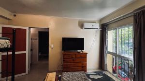 a bedroom with a television on a dresser with a window at Sumaq Hostel Backpackers in Buenos Aires