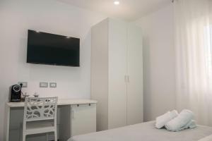 a white bedroom with a desk and a television on the wall at Donna Marianna in Vieste