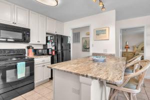 a kitchen with white cabinets and a granite counter top at #7 Ocean Court by Oak Island Accommodations in Caswell Beach