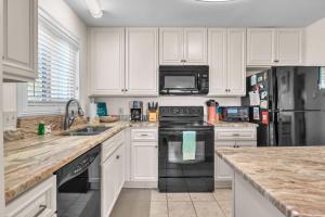a kitchen with white cabinets and black appliances at #7 Ocean Court by Oak Island Accommodations in Caswell Beach