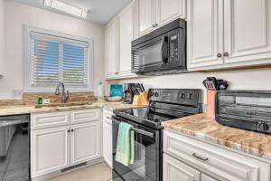a kitchen with white cabinets and black appliances at #7 Ocean Court by Oak Island Accommodations in Caswell Beach