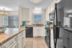 a kitchen with white cabinets and a black refrigerator at #7 Ocean Court by Oak Island Accommodations in Caswell Beach +55 photos