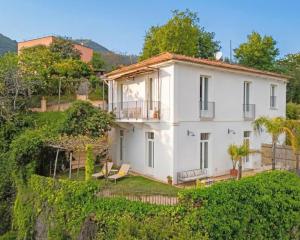 a white house on a hill with chairs and trees at Villa Ipomea - Cielo Suite in Salerno