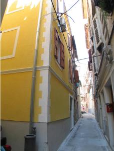 a yellow and white building on a narrow alley at Apartments Bevk in Piran