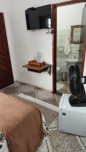 a bedroom with a bed and a tv on the wall at Suítes da Praça Tiradentes in Tiradentes