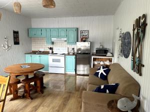 a kitchen with blue cabinets and a couch and a table at Centre de Vacances 5 Étoiles Family Resort in Sacré-Coeur-Saguenay