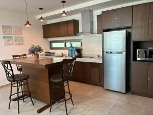 a kitchen with a refrigerator and a table and chairs at La Poza Condominio in Isla Mujeres