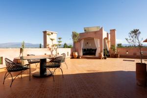 a patio with a table and chairs in front of a building at Riad Zinaida in Aït Bou Zguia