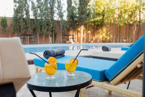 two glasses of orange juice on a table next to a pool at Riad Zinaida in Aït Bou Zguia