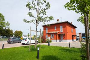 an orange house with cars parked in a parking lot at Il Nido Verde Parcheggio Privato Cortile in Piacenza