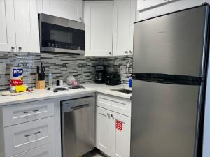 a kitchen with white cabinets and a stainless steel refrigerator at 3315-Magic StudioCondo near Universal in Orlando