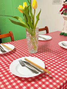 a table with plates and a vase with a flower at Oneone eleven hostel in Belgrade +26 photos