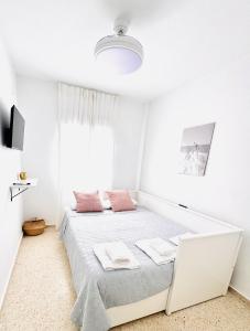 a white bedroom with a bed with pink pillows at Sala 8 Gran Cinema in Sanlúcar de Barrameda +2 photos