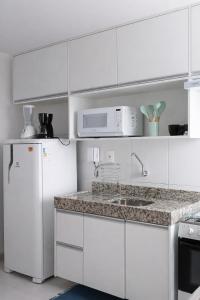 a white kitchen with a refrigerator and a microwave at Paiva Ocean View - 17th Floor with Pool, Sauna & Jacuzzi in Recife