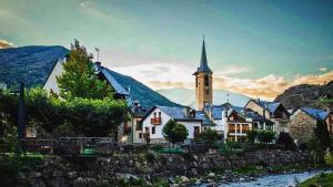 a small town with a church and a river at Acojedor dúplex en la naturaleza in Valencia de Aneu