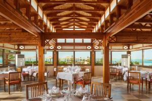 a dining room with tables and chairs and windows at Sea Star Beau Rivage Hotel in Hurghada