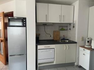 a kitchen with white cabinets and a stainless steel refrigerator at Appartement Linda in Rheinfelden
