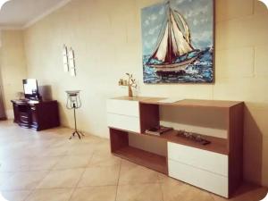 a living room with a painting of a sailboat on the wall at Comfy & Spacious 1BDR 3 Min to Beach in Marsalforn +6 photos