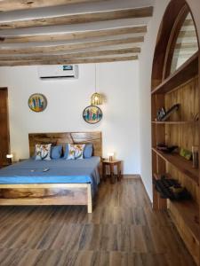 a bedroom with a blue bed and wooden floors at Hakuna Marika in Umbuji